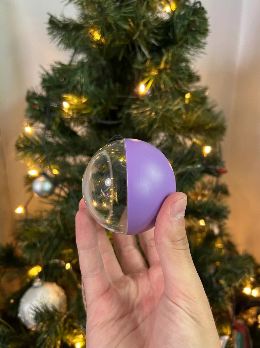 Purple Noel Orb held in hand, showing the glass side